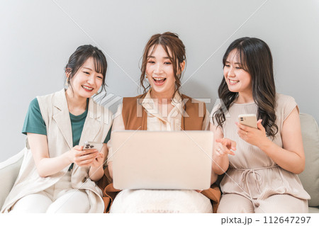 家で一緒にスマホとノートパソコンを使う女性・友達・ママ友・仲間 112647297