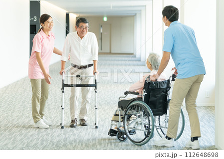 車いすの高齢者と介護する若いヘルパー 車いすの高齢者と介護する若いヘルパー 112648698
