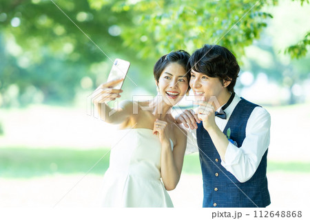 スマホで写真を撮る新郎新婦 112648868
