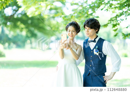 スマホで自撮りをする新郎新婦 112648880