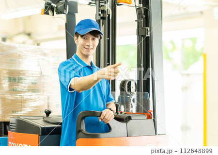 倉庫でフォークリフトを運転する男性 112648899