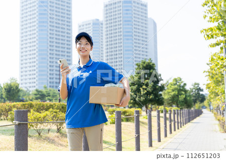 荷物を運ぶ宅配便の若い女性スタッフ 112651203