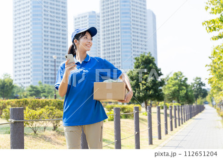 荷物を運ぶ宅配便の若い女性スタッフ 112651204