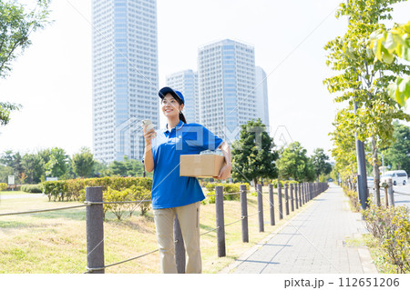 荷物を運ぶ宅配便の若い女性スタッフ 荷物を運ぶ宅配便の若い女性スタッフ 112651206