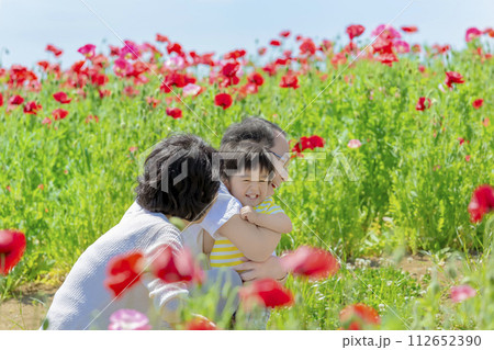 ポピーの咲く公園で孫と遊ぶ祖父母 112652390
