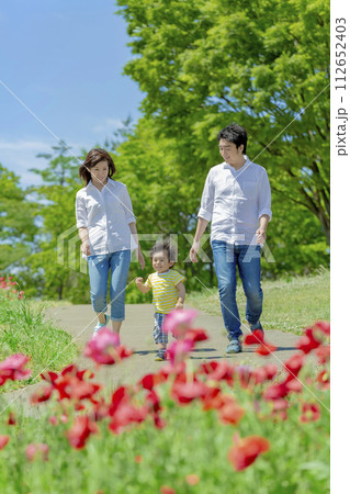 ポピーの咲く公園を歩く3人家族 112652403