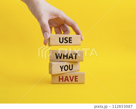 Use what you Have symbol. Concept words Use what you Have on wooden blocks. Beautiful yellow background. Businessman hand. Business and Use what you Have concept. Copy space. 112653087