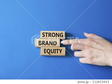 Strong Brand Equity symbol. Concept words Strong Brand Equity on wooden blocks. Businessman hand. Beautiful blue background. Business and Strong Brand Equity concept. Copy space 112653431