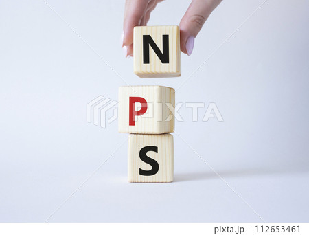 NPS - Net Promoter Score symbol. Wooden cubes with words NPS. Businessman hand. Beautiful white background. Business and NPS concept. Copy space. 112653461