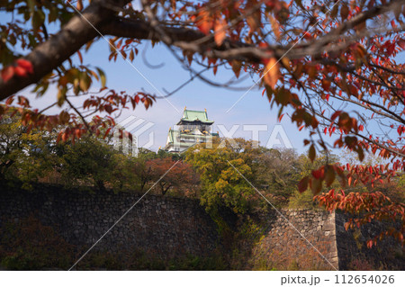 Osaka Castle building with colorful maple leaves or fall foliage in autumn season. Colorful trees, Osaka City, Japan. Architecture landscape background. Famous tourist attraction. Osaka Castle building with colorful maple leaves or fall foliage in autumn season. Colorful trees, Osaka City, Japan. Architecture landscape background. Famous tourist attraction. 112654026