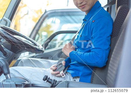 シートベルトを装着する男性トラックドライバー 112655079