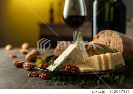Cheese, bread, red wine, and walnuts on a kitchen table. Cheese, bread, red wine, and walnuts on a kitchen table. 112657555