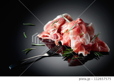 Italian prosciutto or Spanish jamon with rosemary. Italian prosciutto or Spanish jamon with rosemary. 112657575