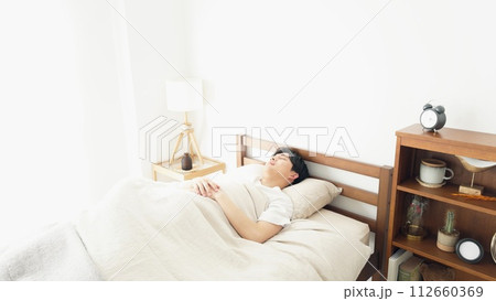 目覚まし時計が鳴って起きる男性 112660369