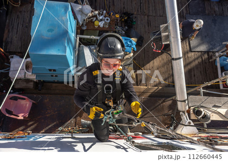 Woman hanging on ropes and working as an industrial alpinist Woman hanging on ropes and working as an industrial alpinist 112660445