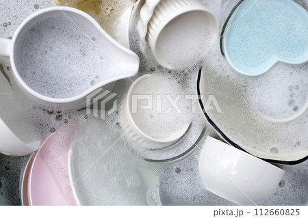 Dishes and bowls in water and bubbles of dishwashing liquid. Kitchen work 112660825