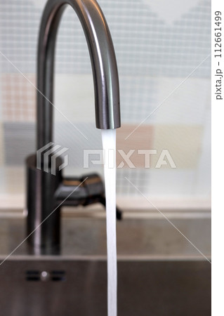 Water flowing out of a stainless steel tap. Kitchen room 112661499