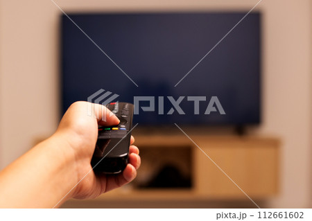 Hand holding TV remote control Hand holding TV remote control 112661602