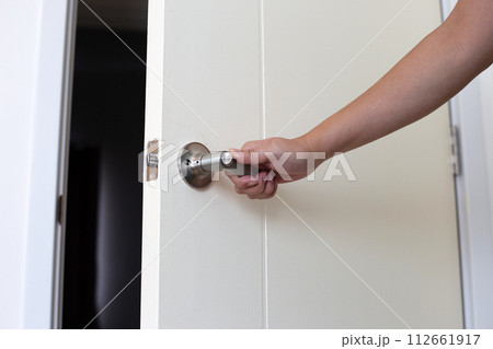 The man's hand is opening the door of the room. 112661917