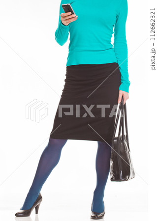 Elegantly dressed business woman holding bag and using smartphone Elegantly dressed business woman holding bag and using smartphone 112662321