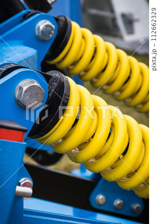 Steel yellow spring as part of blue agricultural machine. Technology Steel yellow spring as part of blue agricultural machine. Technology 112662329
