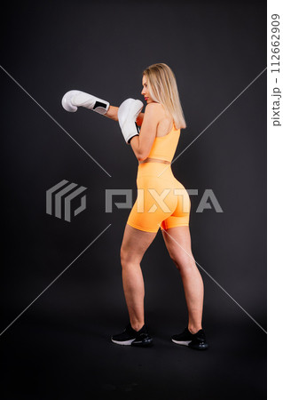 Female boxer hitting at a boxing studio. Woman in gloves training hard. 112662909