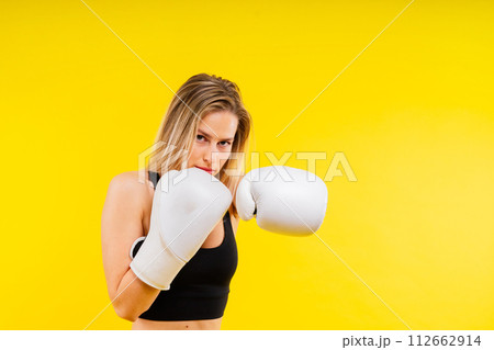 Female boxer hitting at a boxing studio. Woman in gloves training hard. Female boxer hitting at a boxing studio. Woman in gloves training hard. 112662914