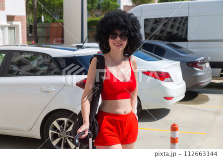 A tourist girl is waiting for a taxi near the hotel for a trip to the airport 112663144