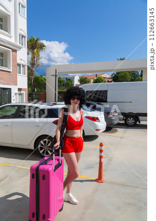 A tourist girl is waiting for a taxi near the hotel for a trip to the airport 112663145