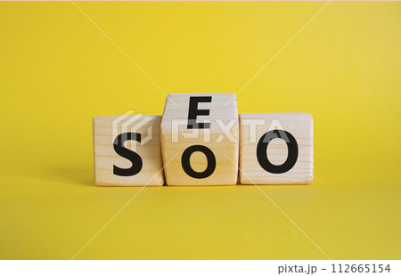 SEO vs SOO symbol. Wooden cubes with words SOO and SEO. Beautiful yellow background. SEO vs SOO and business concept. Copy space 112665154
