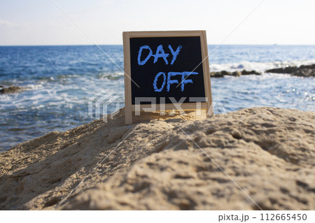 Day off symbol. Day off black chalk blackboard. Beautiful sea background. Business and Day off concept. Copy space. Day off symbol. Day off black chalk blackboard. Beautiful sea background. Business and Day off concept. Copy space. 112665450