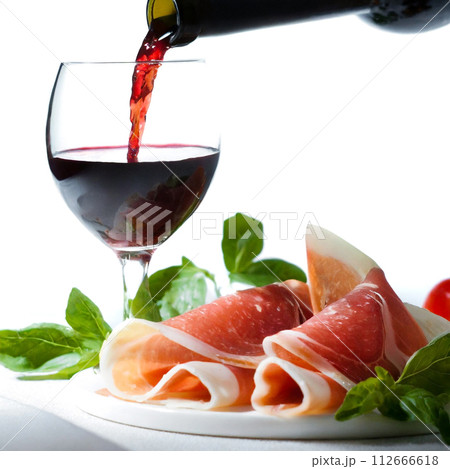 生ハムとワイングラスに注がれる赤ワイン 112666618