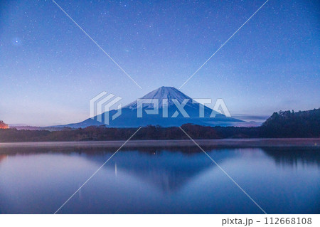（山梨県）車のライトが湖上の霧を照らし、幻想的な景色になった精進湖と富士山 112668108