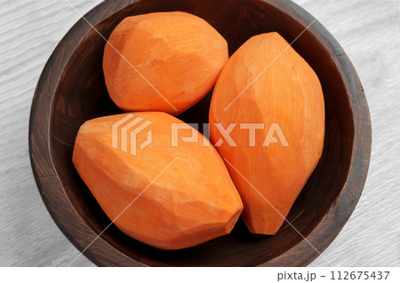 Raw whole organic peeled sweet potatoes in wooden bowl. Fresh vegetable root close up. Top view. Raw whole organic peeled sweet potatoes in wooden bowl. Fresh vegetable root close up. Top view. 112675437