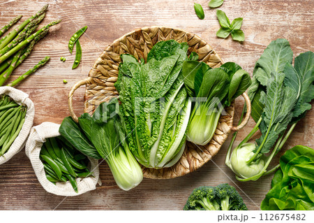 Vegetables background. Various vegetables in a basket on kitchen table. Clean eating, healthy food concept, flat lay, top down view 112675482