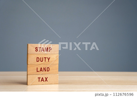 Stamp duty land tax SDLT concept. Taxes assessed during the transfer of real estate between two parties. Buying housing and land. Property. Wooden blocks Stamp duty land tax SDLT concept. Taxes assessed during the transfer of real estate between two parties. Buying housing and land. Property. Wooden blocks 112676596