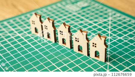 Miniature houses on a cutting mat. Home renovation and reconstruction concept. Construction of real estate and new housing. Maintenance house. Close up, selective focus Miniature houses on a cutting mat. Home renovation and reconstruction concept. Construction of real estate and new housing. Maintenance house. Close up, selective focus 112676659