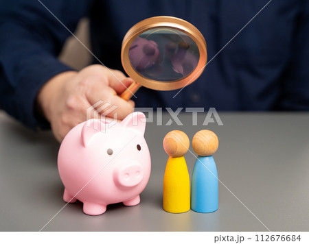 A man holds a piggy bank in his hands near people of Ukrainian nationality. Budget of Ukraine and assistance to residents. Providing money, paying salaries and grants. Compensation payments. 112676684