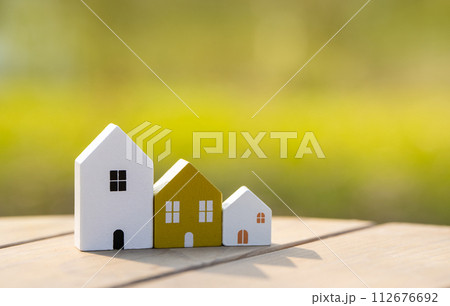 Wooden houses stand in a row outdoors on a sunny day. Real estate and affordable housing concept. Mortgage, loan. Eco-friendly house 112676692