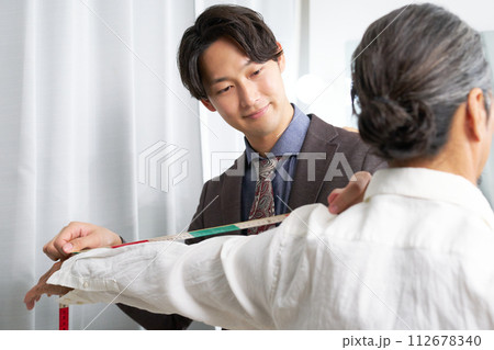 採寸をするスーツショップの店員 112678340