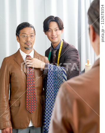 鏡の前でネクタイを選ぶお客と店員 112678354