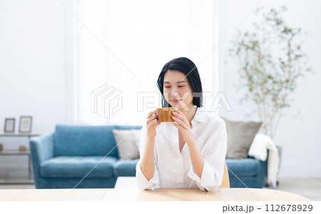 リビングでコーヒーを飲む若い女性 リビングでコーヒーを飲む若い女性 112678929