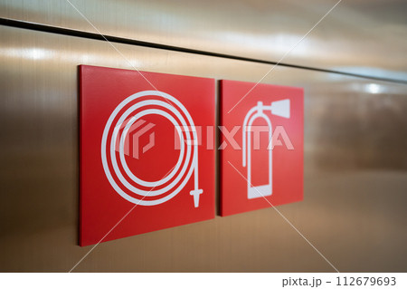 Fire Hose and fire extinguisher signs on the wall 112679693