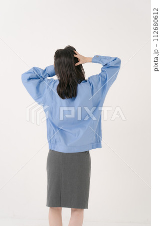 頭を抱える作業員の女性の後ろ姿 112680612