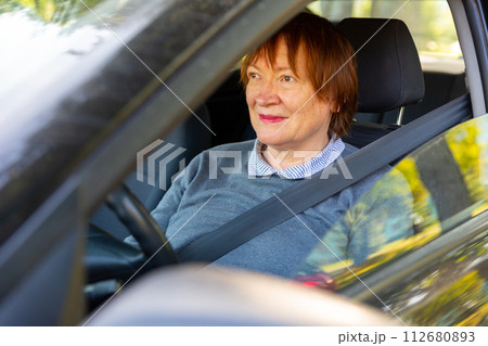Positive mature woman sitting inside her car Positive mature woman sitting inside her car 112680893