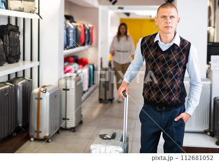 Positive man chose suitcase in haberdashery store 112681052
