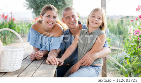 Happy family sits at table in backyard of summer cottage 112681725