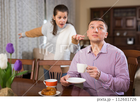 Man ignoring disgruntled wife reprimanding him Man ignoring disgruntled wife reprimanding him 112681726