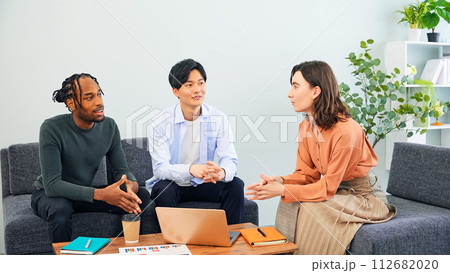 ロビーでノートパソコンを見ながら会話する多国籍の人々 ロビーでノートパソコンを見ながら会話する多国籍の人々 112682020