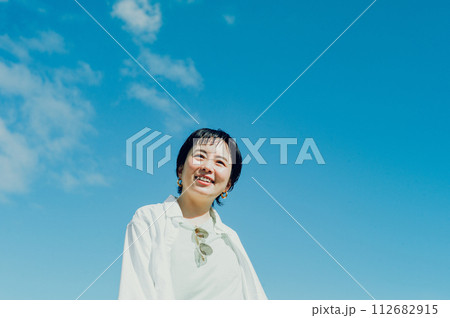 外で青空の下で微笑んでいるショートカットのおしゃれな女性 外で青空の下で微笑んでいるショートカットのおしゃれな女性 112682915